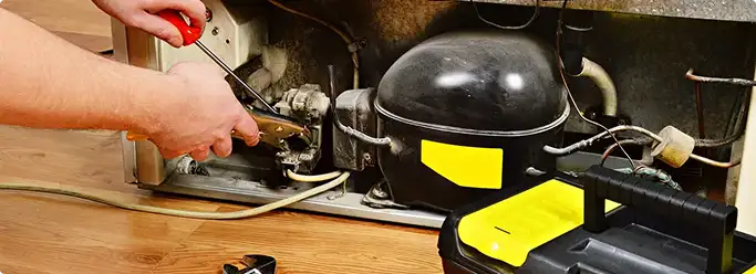 Refrigerator repair technician fixing the compressor and wiring in Ellenton, FL