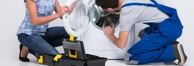 Washer repair technician inspecting a front-load washing machine with tools in Bradenton, FL