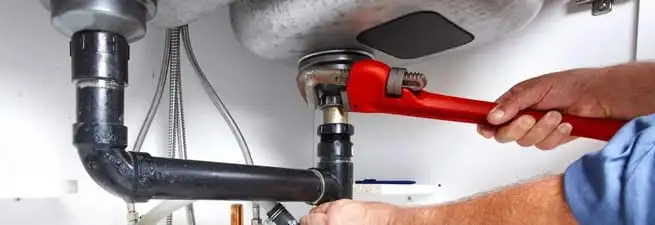 Garbage disposal repair technician tightening the sink drain and disposal connection in Bradenton, FL