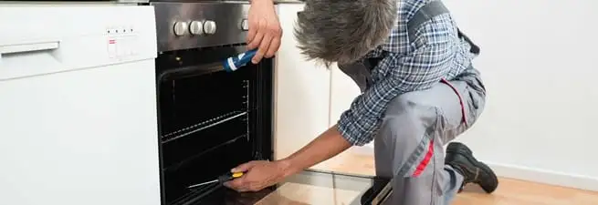 Oven repair technician inspecting and servicing an electric oven in Bradenton, FL