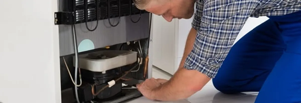 Refrigerator repair technician servicing the compressor and condenser area in Bradenton, FL