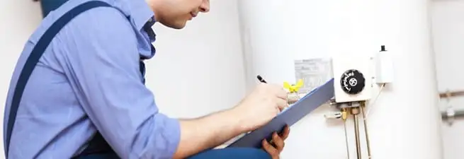 Water heater repair technician inspecting the unit and recording service notes in Bradenton, FL